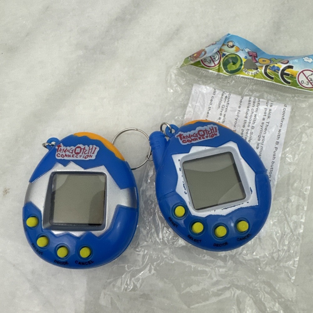 2 Collectors Tamagotchi With Crack On Plastic On Right Side Still Works